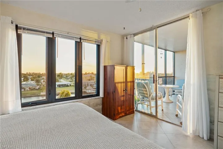 Bedroom with access to exterior, a textured ceiling, light tile patterned floors, and expansive windows