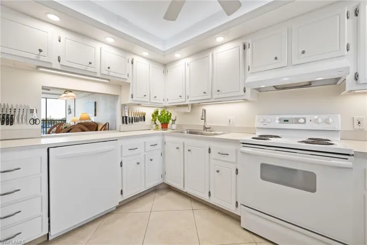 Kitchen with white appliances, light countertops, white cabinets, and recessed lighting