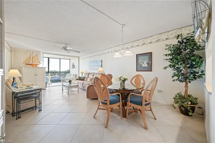 Dining space with a textured ceiling, a ceiling fan, light tile patterned floors, and expansive windows