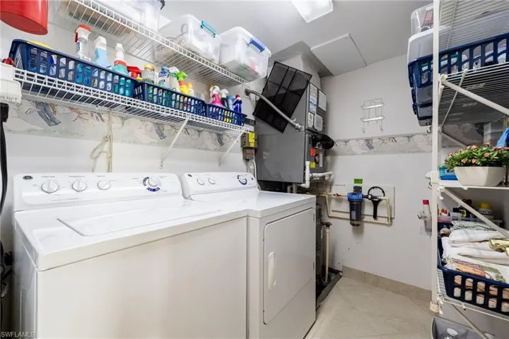 Laundry room with separate washer and dryer, light tile patterned floors, and heating unit