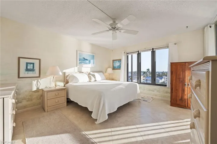 Bedroom with a textured ceiling, a ceiling fan, and light tile patterned floors