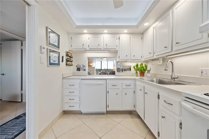 Kitchen with white cabinets, light countertops, dishwasher, recessed lighting, and a tray ceiling