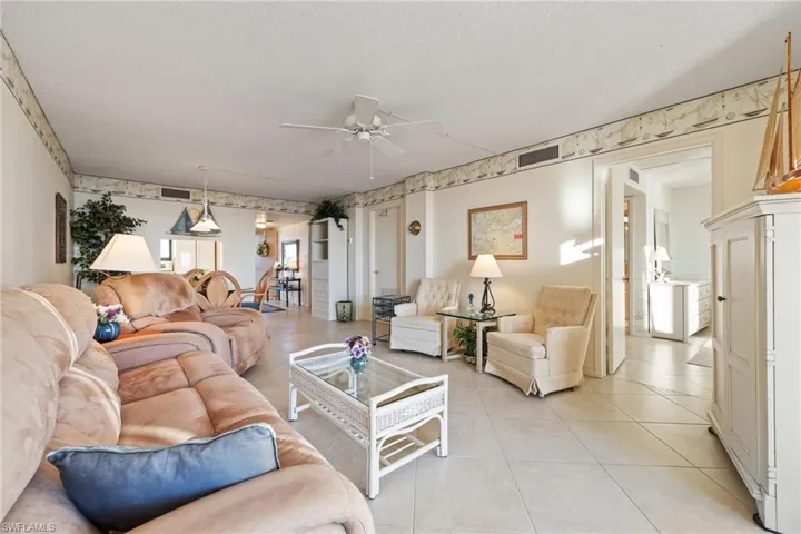 Living room featuring ceiling fan, a textured ceiling, and light tile patterned floors