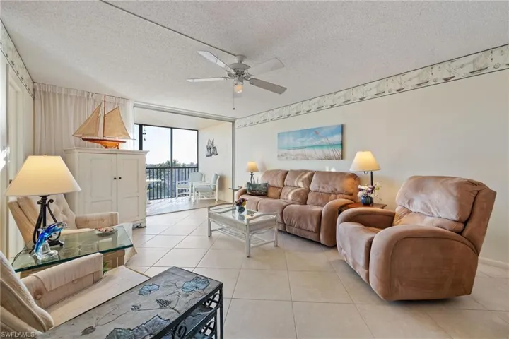 Living area featuring ceiling fan, a textured ceiling, light tile patterned flooring, and expansive windows