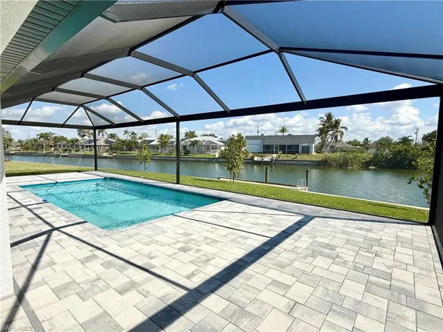 View of swimming pool with a water view, a patio, and glass enclosure