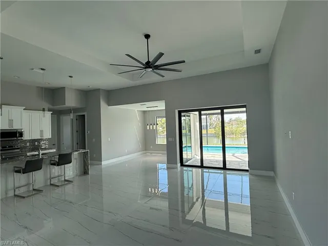 Kitchen with appliances with stainless steel finishes, a kitchen bar, a tray ceiling, and white cabinets