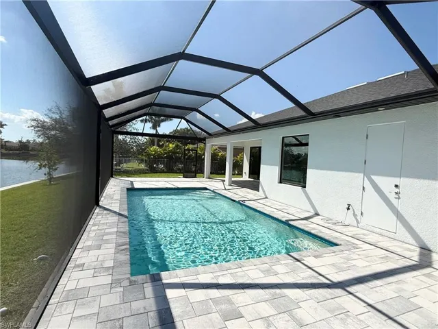 View of swimming pool featuring a lanai, a patio area, and a water view