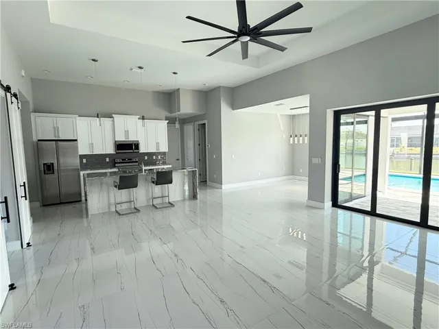Kitchen with appliances with stainless steel finishes, white cabinetry, a kitchen breakfast bar, a center island, and a barn door