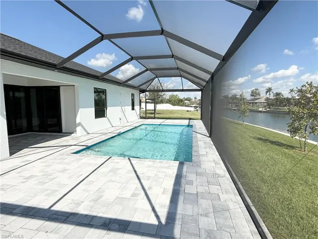 View of swimming pool featuring a yard, a lanai, a patio area, and a water view