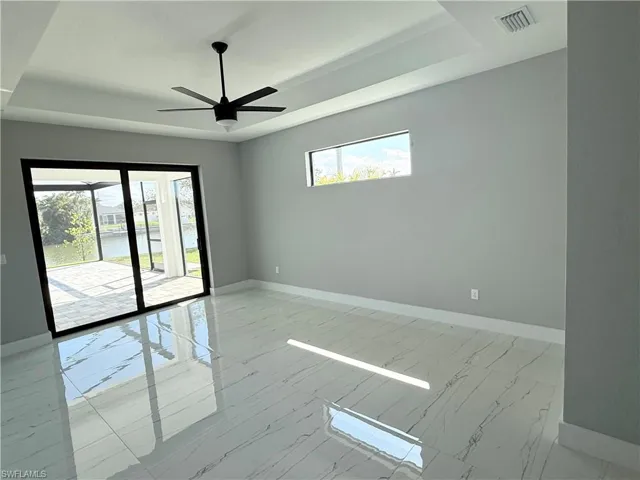 Empty room featuring ceiling fan and a tray ceiling