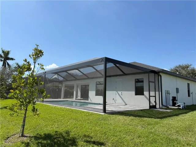 Rear view of house with glass enclosure and a lawn