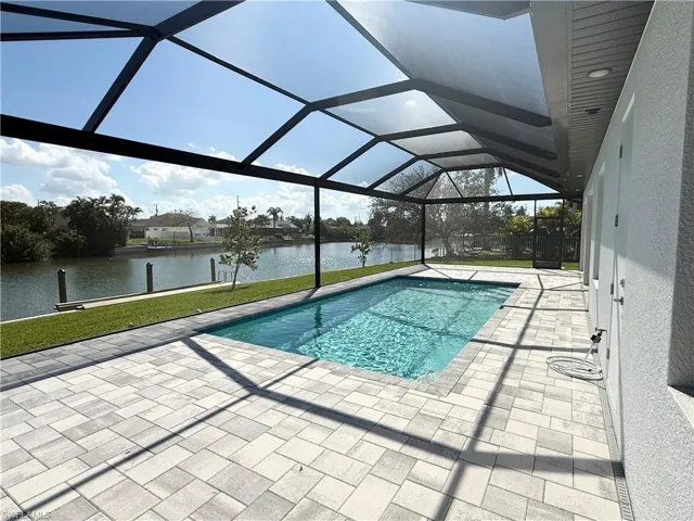 View of swimming pool featuring a water view, a patio area, and a lanai