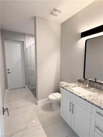 Bathroom with vanity, toilet, and an enclosed shower