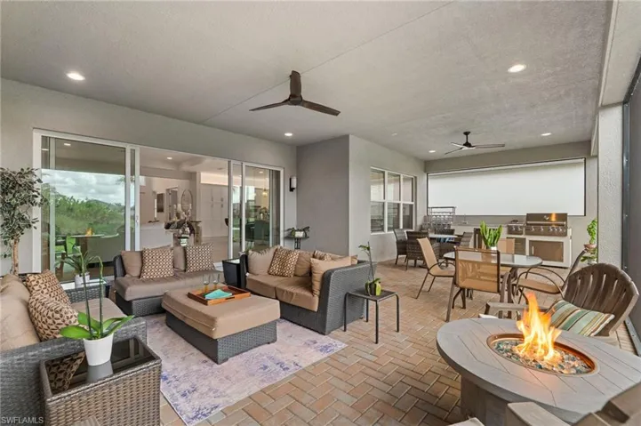 Massive covered and screened lanai with summer kitchen and view of lake, with privacy hedge.