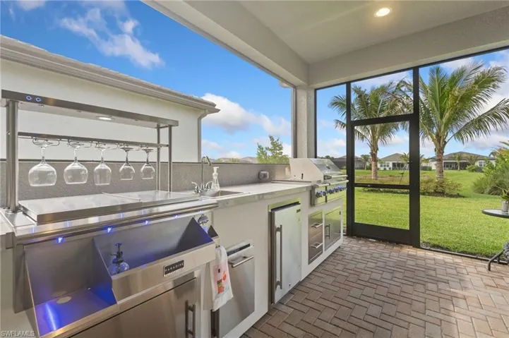 Outdoor summer kitchen with grill, side burners, beverage station, refrigerator, sink.