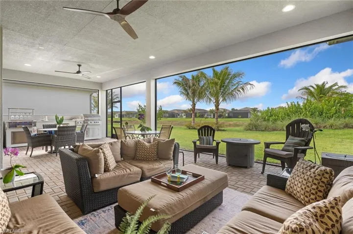 Massive covered and screened lanai with summer kitchen and view of lake, with privacy hedge.