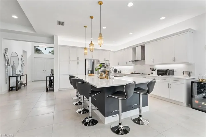 Gourmet kitchen with large island, quartz countertops and quartz backsplash, vented chimney hood, built-in pantry.