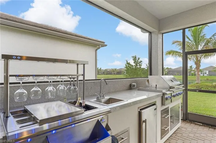 Outdoor wet bar and summer kitchen with natural gas grill, side burners, beverage refrigerator, sink, trash, storage, glass racks, ice bin, garnish inserts, and LED lights.