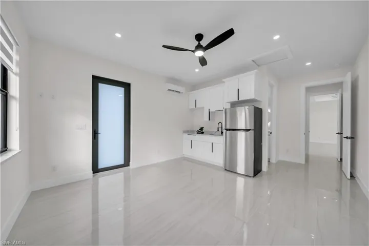 Kitchen featuring white cabinets, freestanding refrigerator, a ceiling fan, light countertops, and recessed lighting