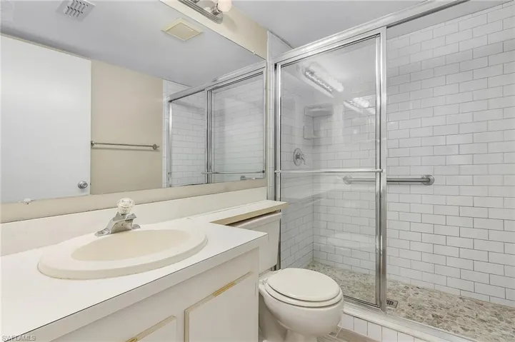 Bathroom featuring a shower with door, vanity, and toilet