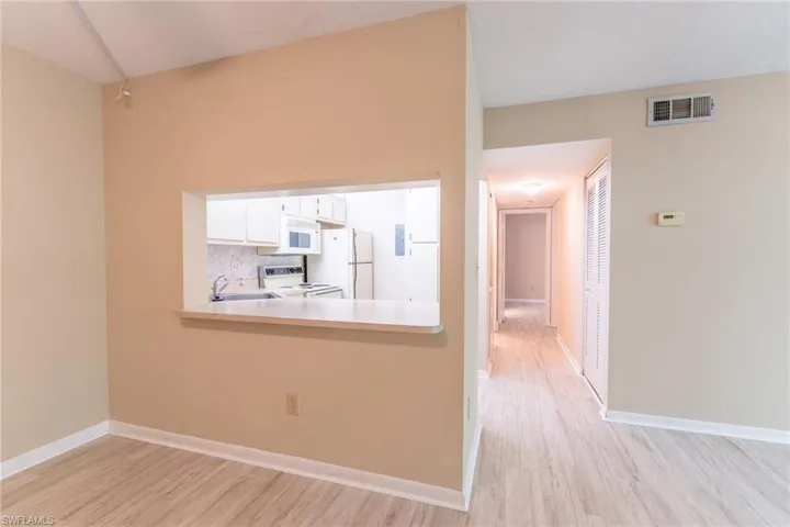 Kitchen with white cabinetry, light hardwood / wood-style flooring, white appliances, backsplash, and sink