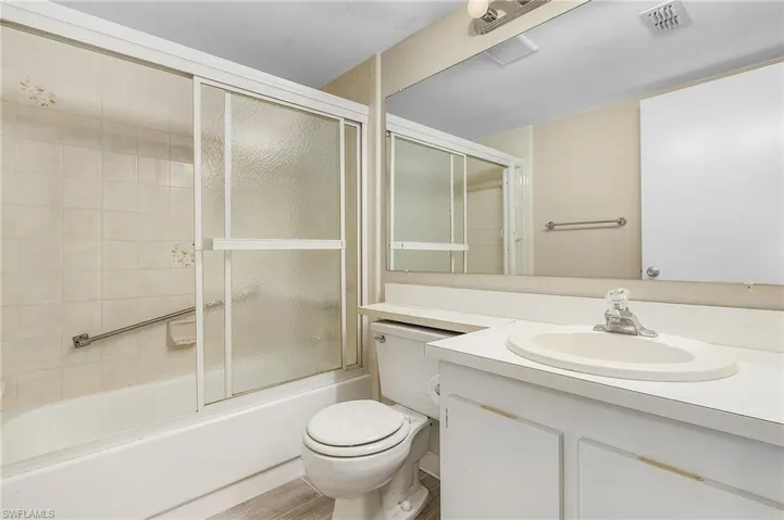 Full bathroom featuring shower / bath combination with glass door, vanity, and toilet