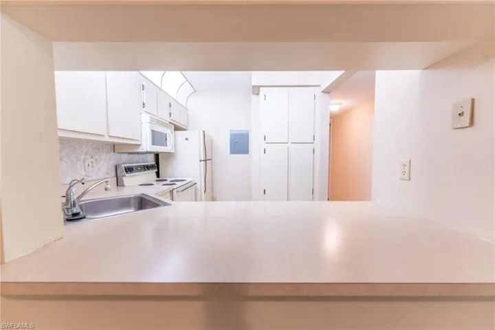 Kitchen with white cabinetry, sink, white appliances, and backsplash