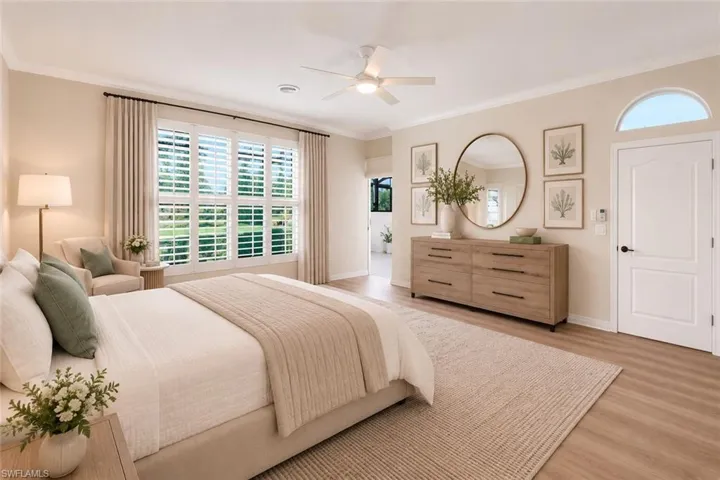 Wood-finish flooring, white plantation shutters, arched transom window, ceiling fan, and crown molding