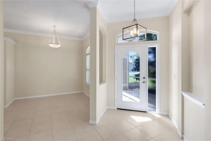 Entry foyer with tile flooring and a transom window, featuring a pendant light fixture