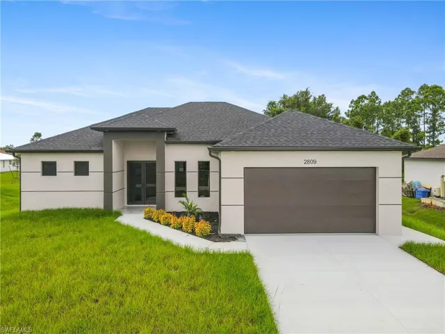 View of front of home featuring a front yard, driveway, an attached garage, stucco siding, and roof with shingles