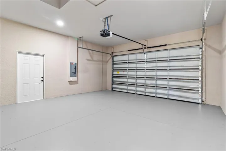 Garage featuring electric panel, a garage door opener, and a textured wall