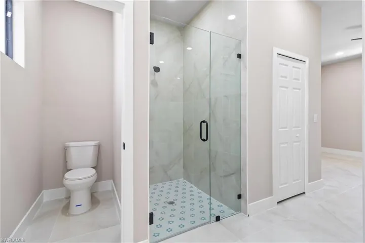 Bathroom featuring a marble finish shower, tile patterned flooring, and recessed lighting