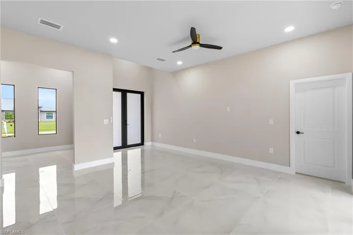 Empty room with french doors, a ceiling fan, light marble finish flooring, and recessed lighting