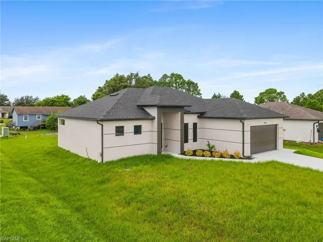 View of front facade featuring a front yard, driveway, and a garage