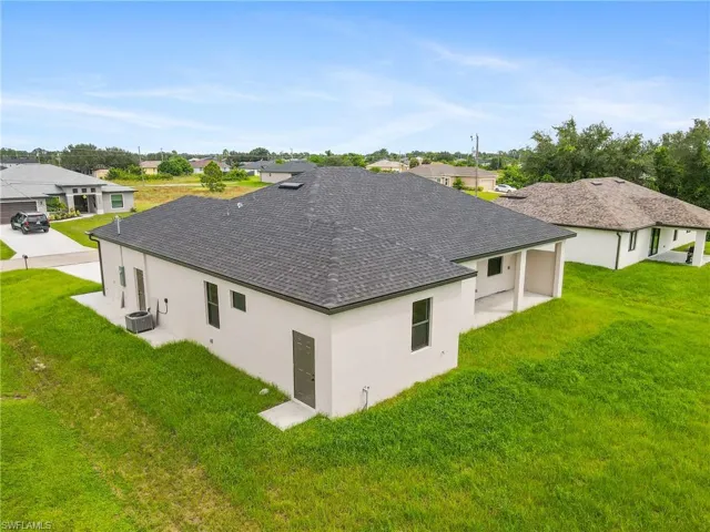 View of property exterior with a yard, stucco siding, roof with shingles, and a patio area