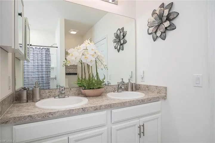 Full bath featuring a shower with shower curtain and double vanity