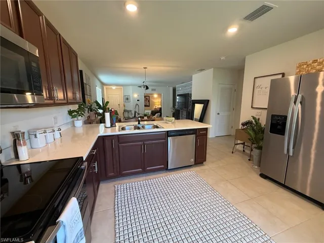 Kitchen featuring stainless steel appliances, pendant lighting, a peninsula, dark brown cabinets, and recessed lighting