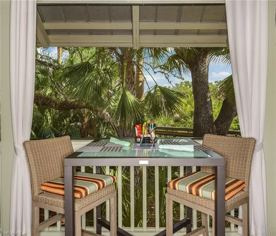An intimate covered dining nook framed by drapery and lush palm views.