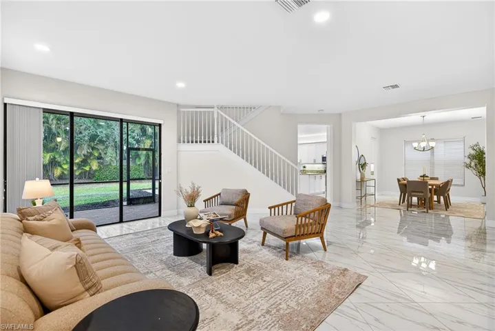 Living room with stairs, plenty of natural light, light marble finish floors, recessed lighting, and a chandelier