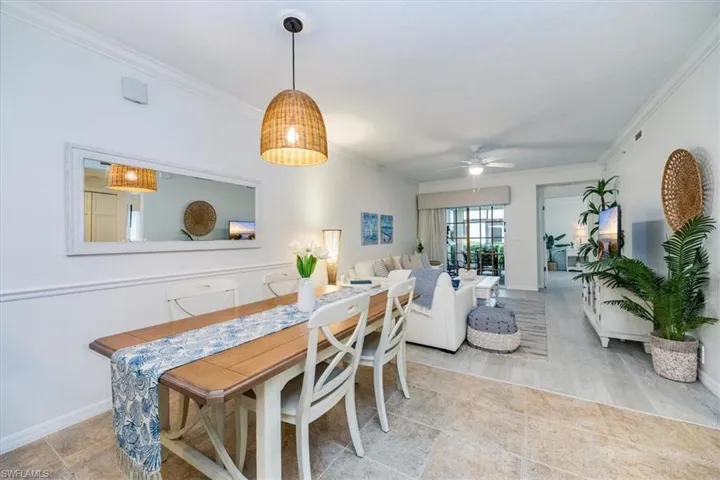Dining space featuring custom light fixture, crown molding, and tile floors (dining table expands)