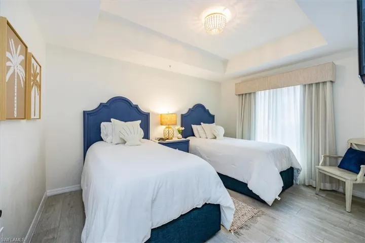 Guest Bedroom featuring two oversized twin beds, tray ceiling and wood-type flooring