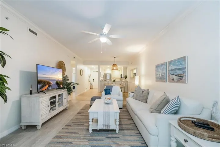 Living room with light hardwood / wood-style floors, ceiling fan, and ornamental molding
