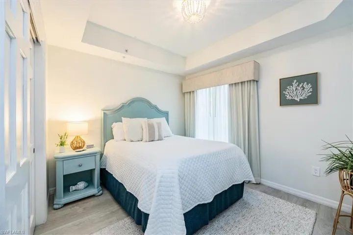 Guest Bedroom with Queen bed, tray ceiling and wood-style flooring