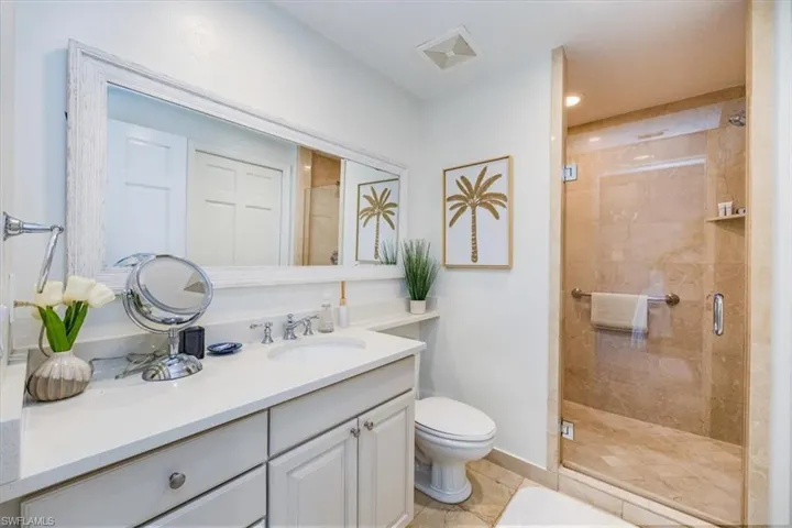 Primary Bathroom with toilet, vanity, an enclosed shower with frameless door (Primary walk in closet and lock out owners closet not shown)