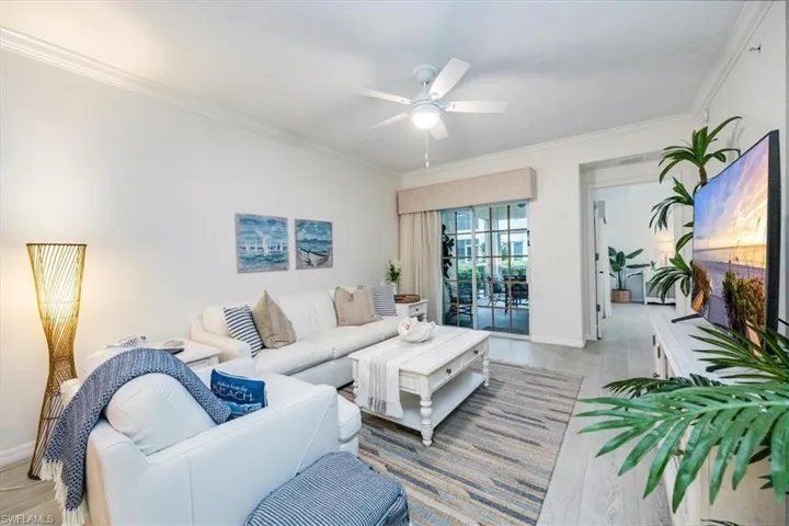 Living room with crown molding, ceiling fan, and light wood-style flooring enjoys direct access to the screened lanai