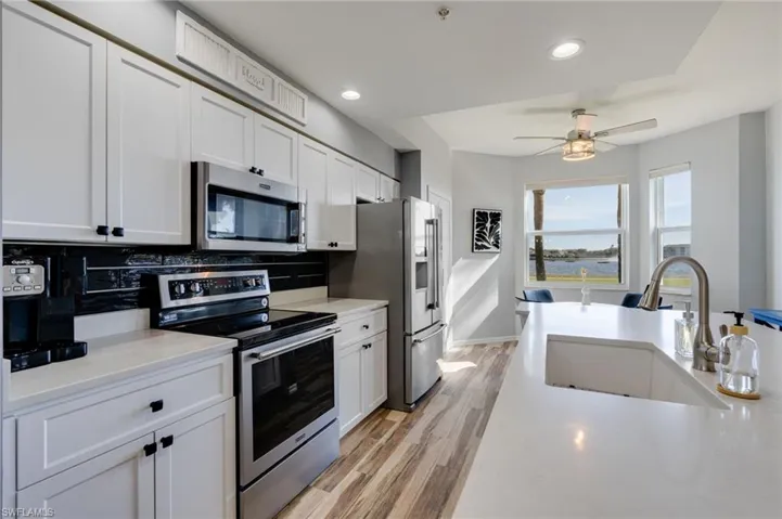 Kitchen with stainless steel appliances, white cabinetry, light wood-style flooring, recessed lighting, and decorative backsplash
