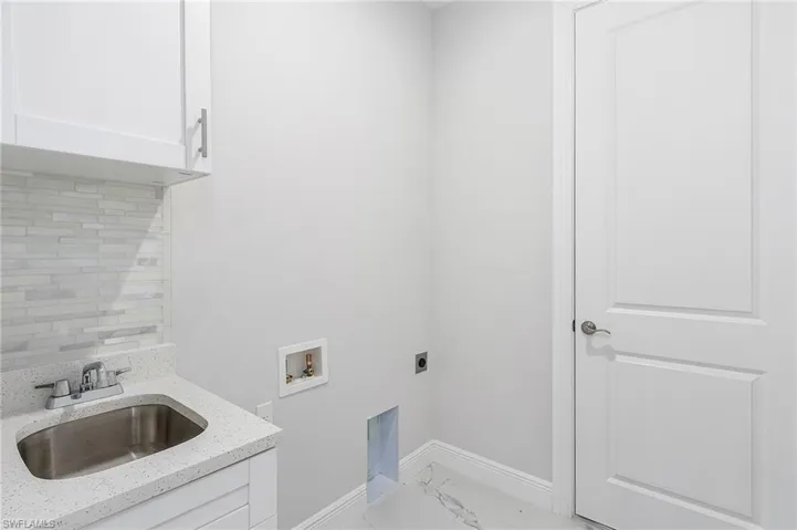 Laundry area with cabinets, washer hookup, hookup for an electric dryer, sink, and light tile flooring