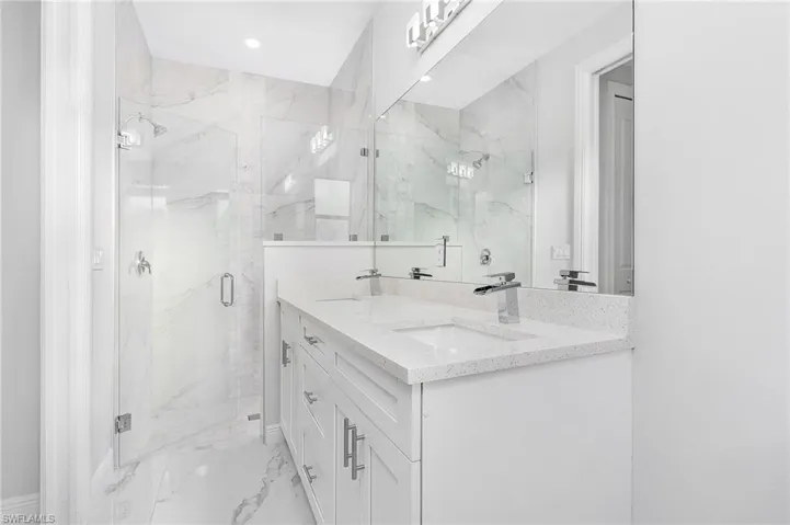 Bathroom featuring vanity with extensive cabinet space and a shower with door
