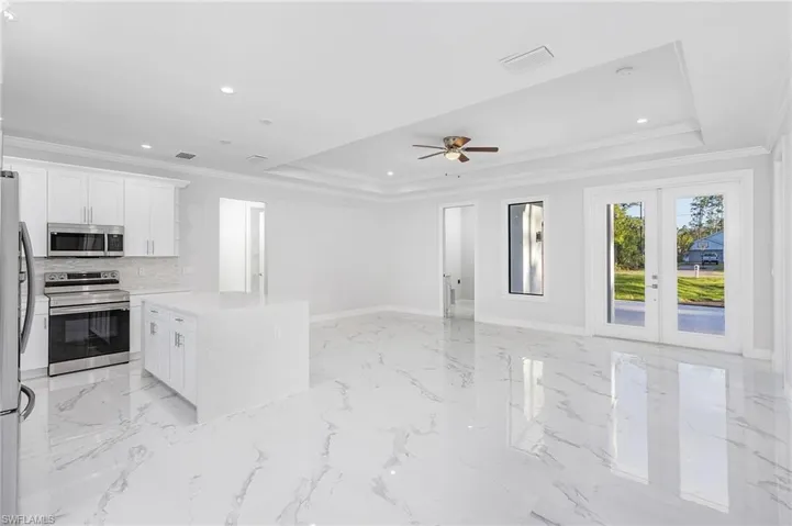 Kitchen featuring appliances with stainless steel finishes, ceiling fan, light tile floors, and a raised ceiling