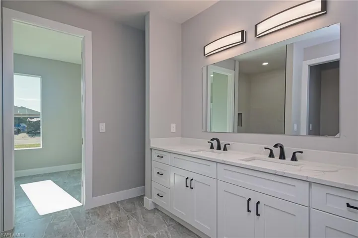 Bathroom with double vanity and baseboards